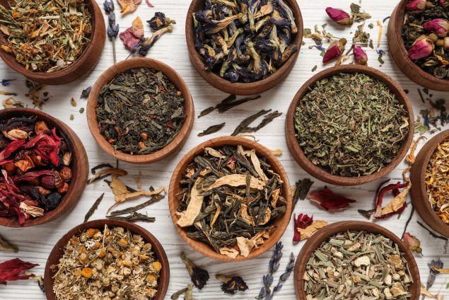 Flat lay composition with different dry teas on white wooden table Flat lay composition with different dry teas on white wooden table